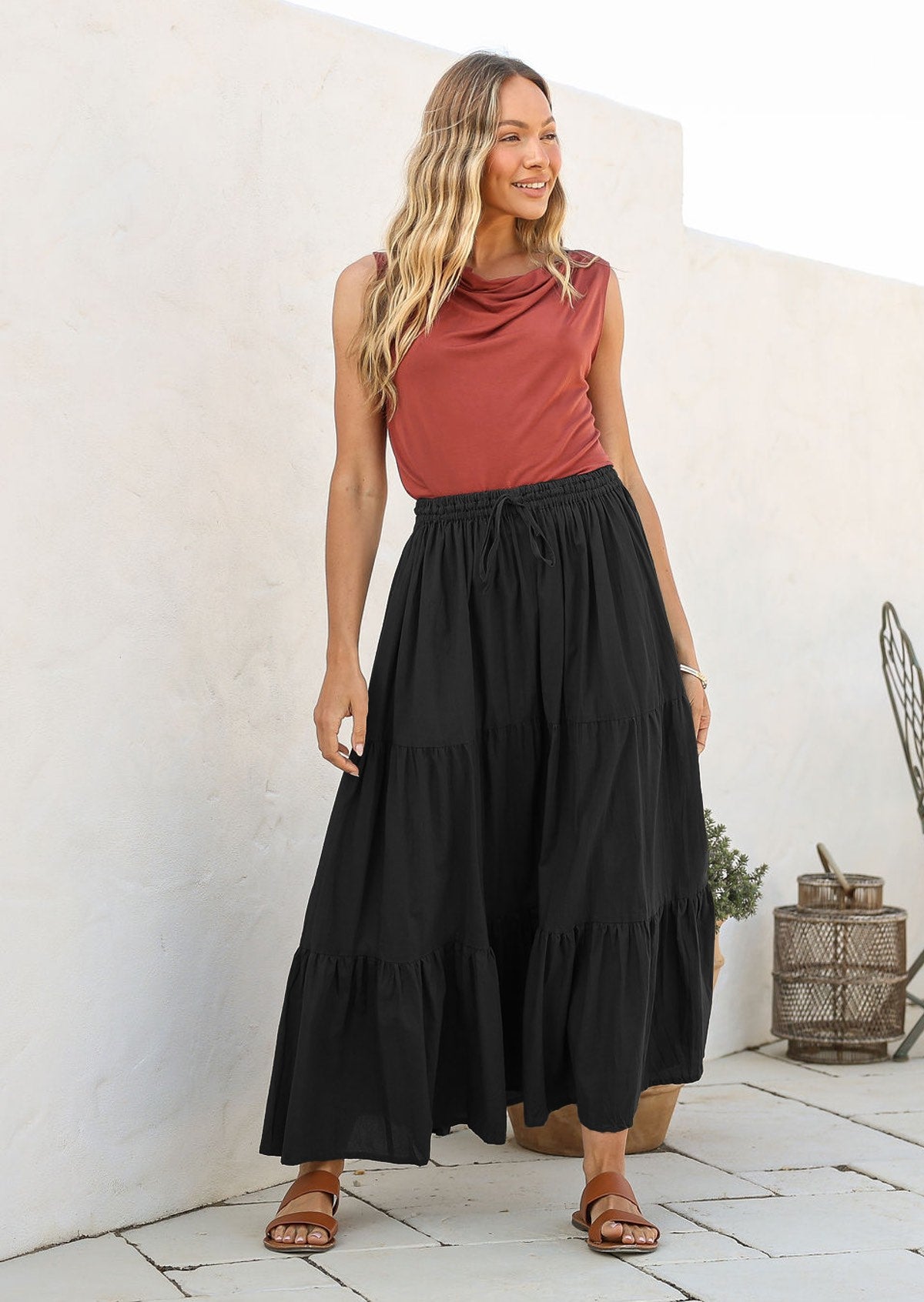 Woman wearing a black cotton maxi skirt with a shoestring tie, paired with a dusty pink sleeveless top