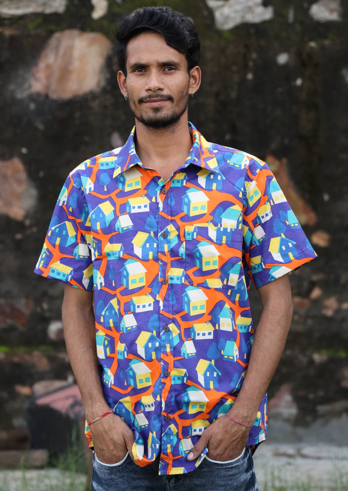 Man stands with hands in pockets in bright house print cotton short sleeve shirt