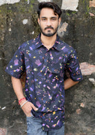 Man leans against wall in cotton short sleeve shirt with fun space themed print on black base