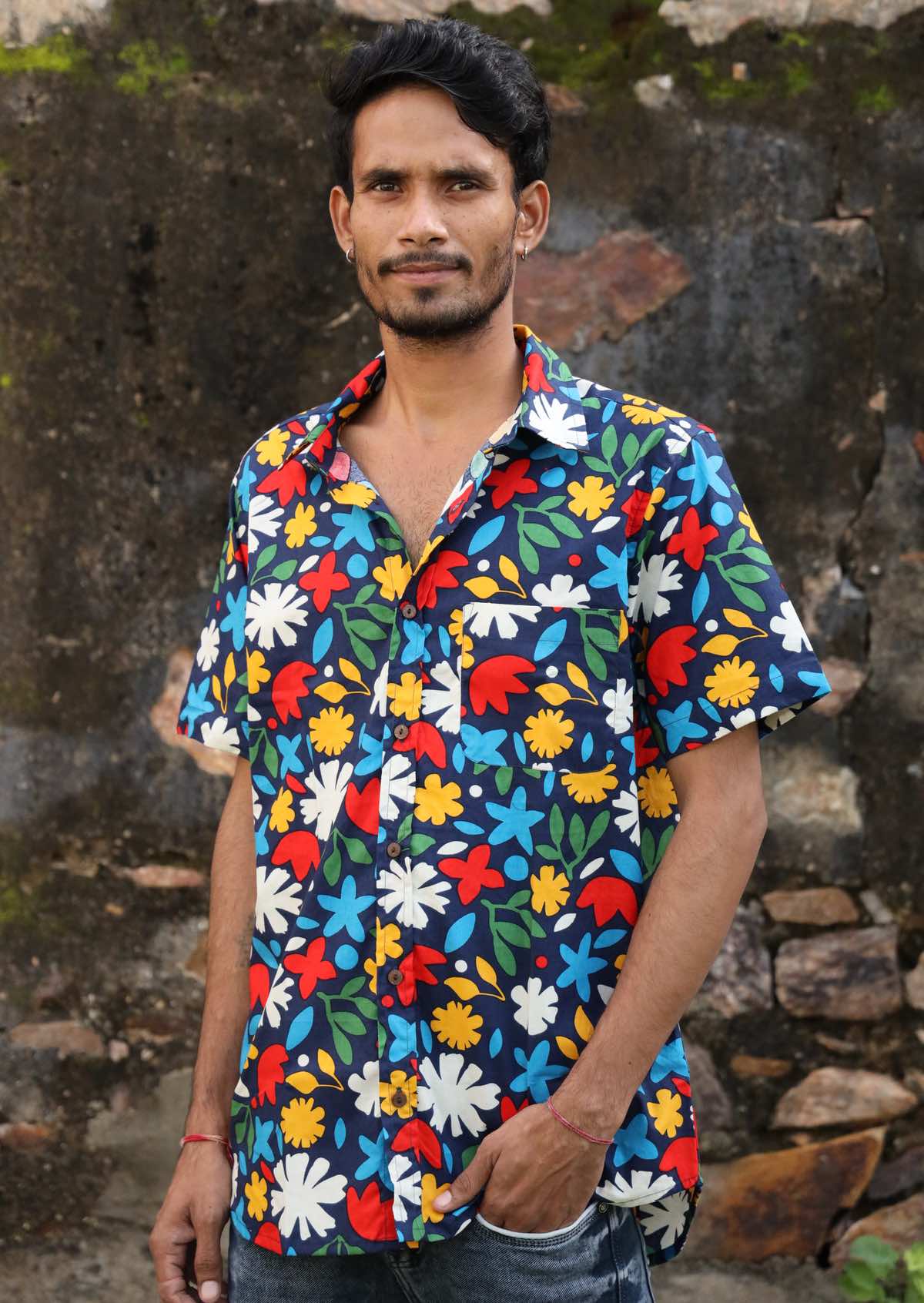 Man wears cotton short sleeve collared shirt in fun bold floral print with coconut buttons