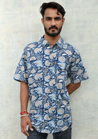 Man poses in blue floral print cotton button through shirt with collar and one breast pocket