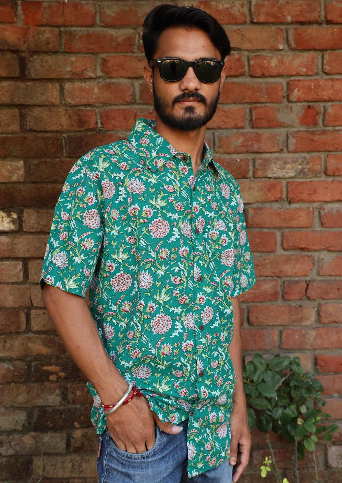 Man poses in short sleeve relaxed fit cotton collared shirt with one breast pocket in green based floral print