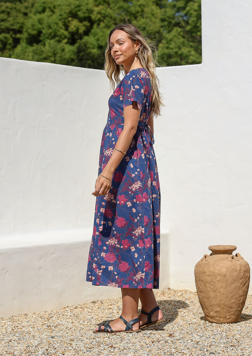 Woman posing in a relaxed fit, short sleeved, blue floral cotton dress with V- neckline, drawstring waist tie and pockets 
