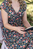 close up of floral print rayon dress on model sitting down showing elasticated neckline