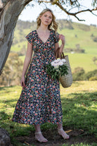 Model holding basket of flowers wearing 100 percent rayon floral maxi dress