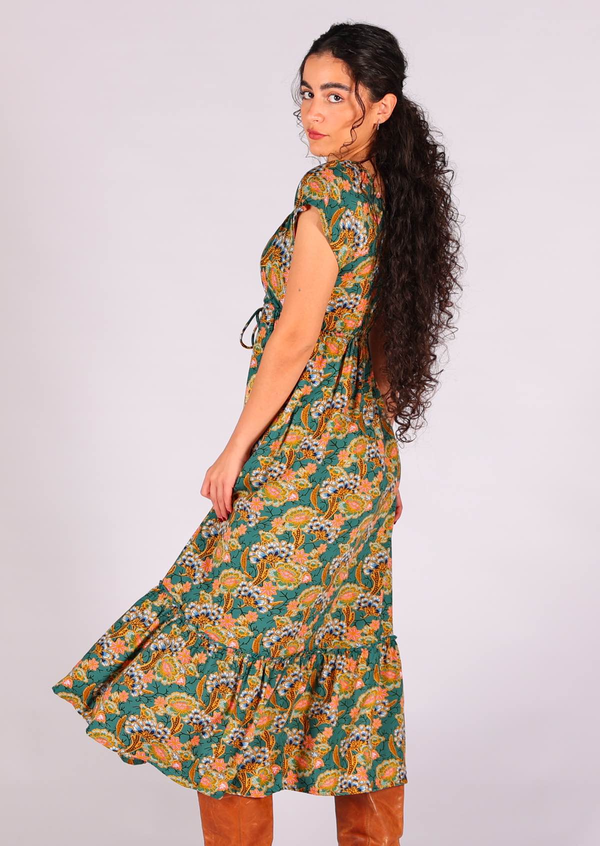 Model looking back over her shoulder wearing 100 percent rayon maxi dress in sweet green based floral print