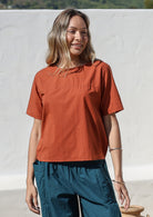 Model wearing a 100% cotton top in rust shade paired with a deep blue pants