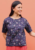 Model wearing T-shirt sleeved, round neck cotton top with floral print on a dark base