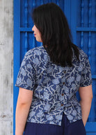 Back view of model wearing floral navy blue boxy blouse 100 percent cotton with decorative buttons going down the back of Neesha top