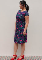 woman in navy and purple floral cotton knee length dress with round neckline empire waist side view