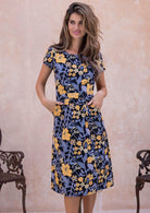 Woman wearing a cap sleeved 100% cotton floral print dress with yellow and grey flowers on the black base.
