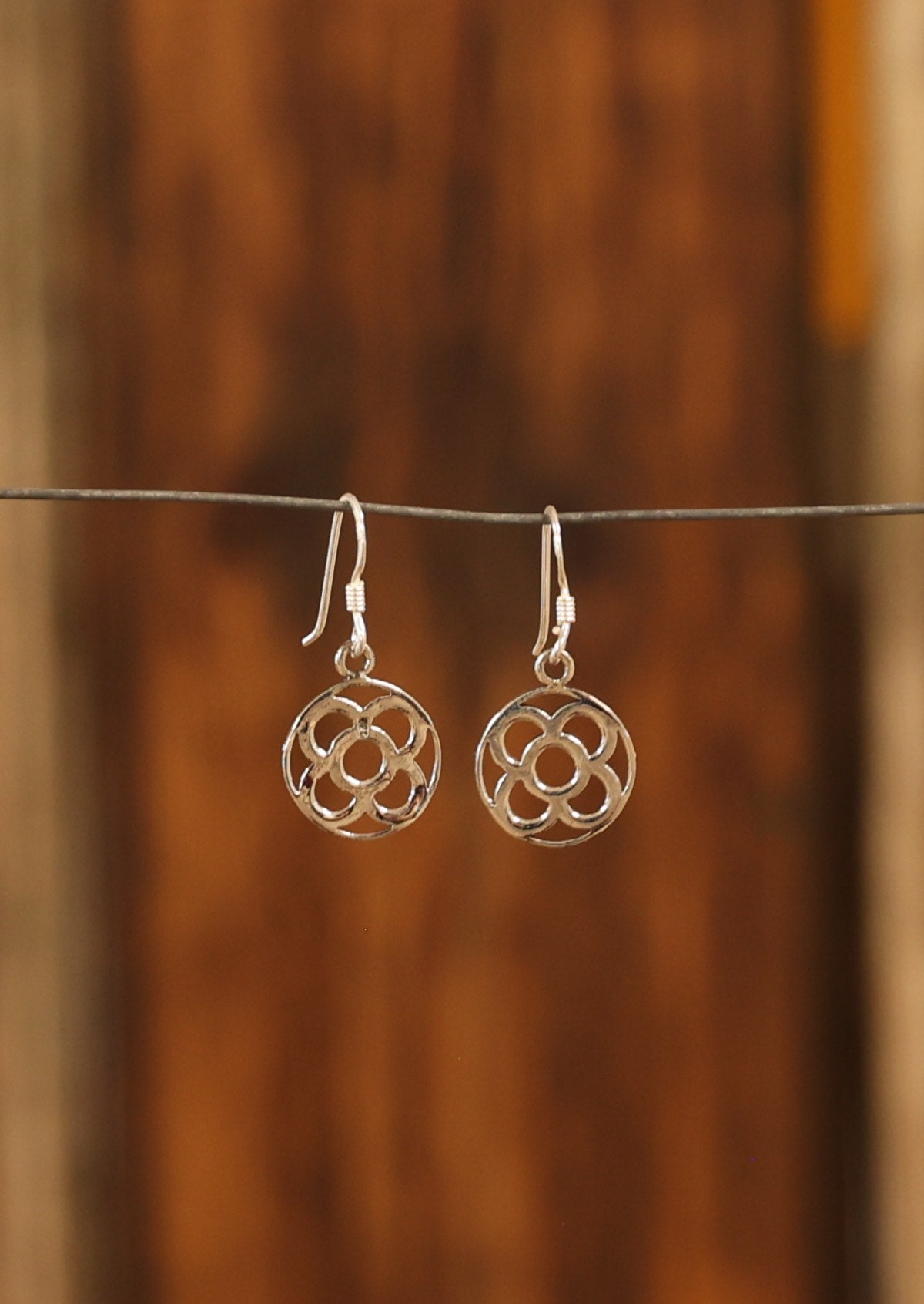 Sterling silver disc earrings with four petal cutout, suspended from wire hooks