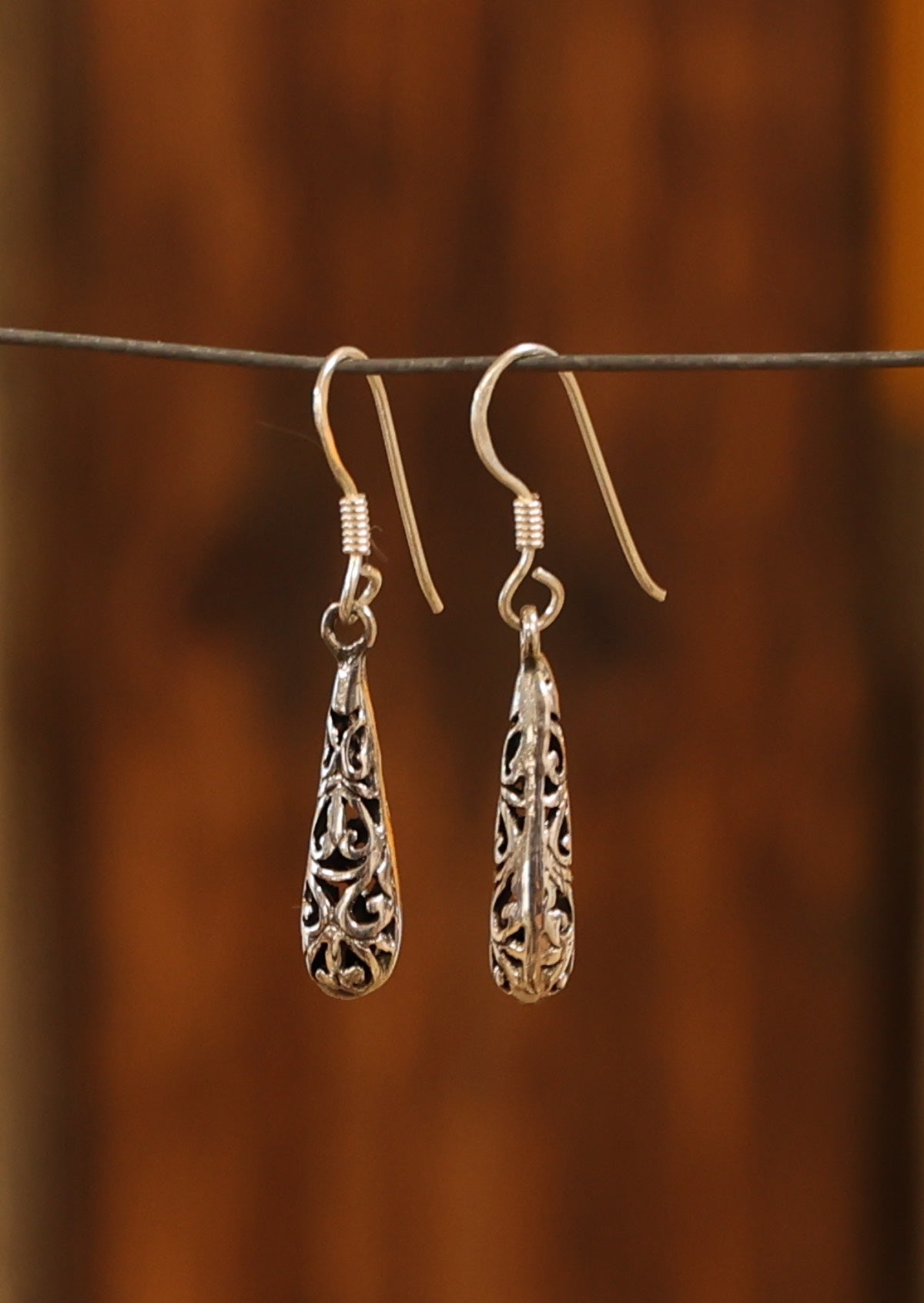 Teardrop shape with ornate details suspended from wire hook