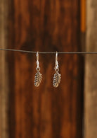 Sterling silver small feather earrings with etched details, suspended on a wire hook