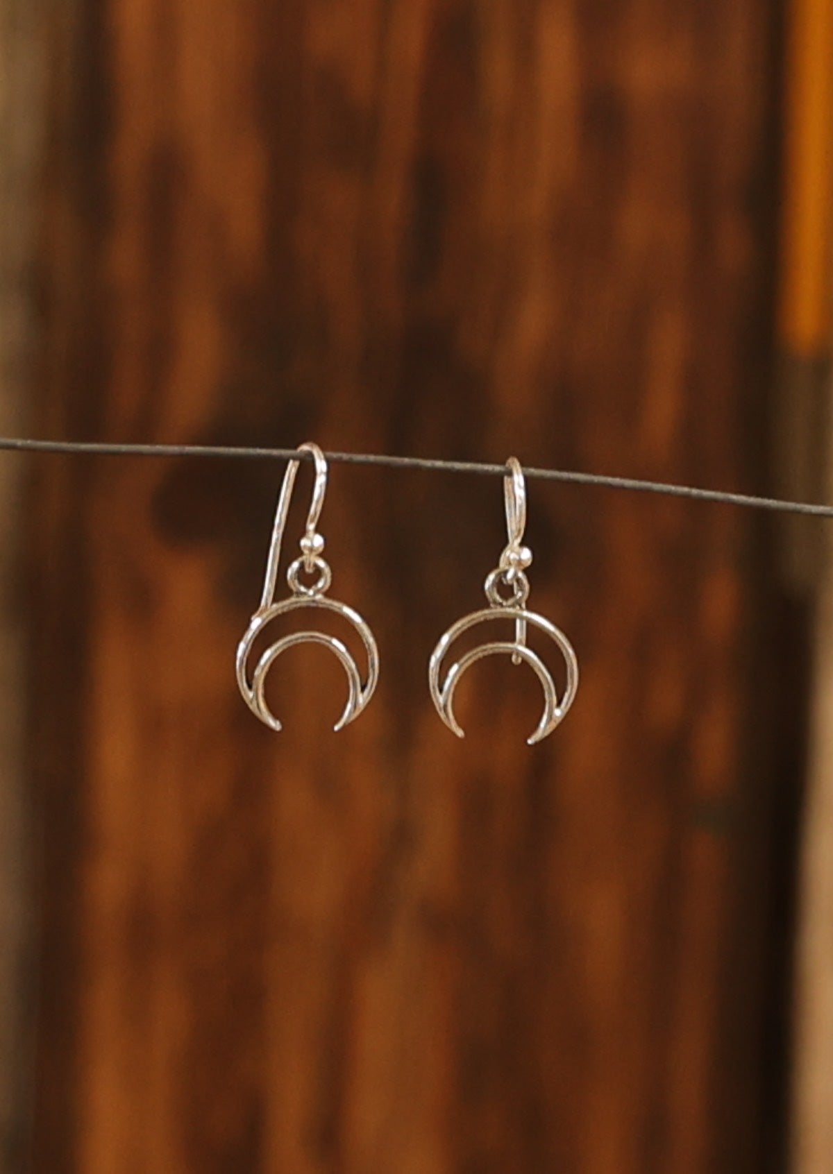 Sterling silver linear crescent moon earrings, hanging from wire hooks