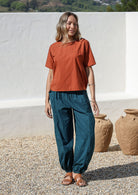 Models poses in deep teal cotton wide leg pants with elasticated ankle