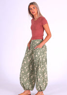 Model wears cotton harem pants in pale green and cream floral print with her hands in pockets