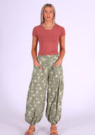 Model wears cotton harem pants with elasticated ankles and wide waistband with her hands in pockets