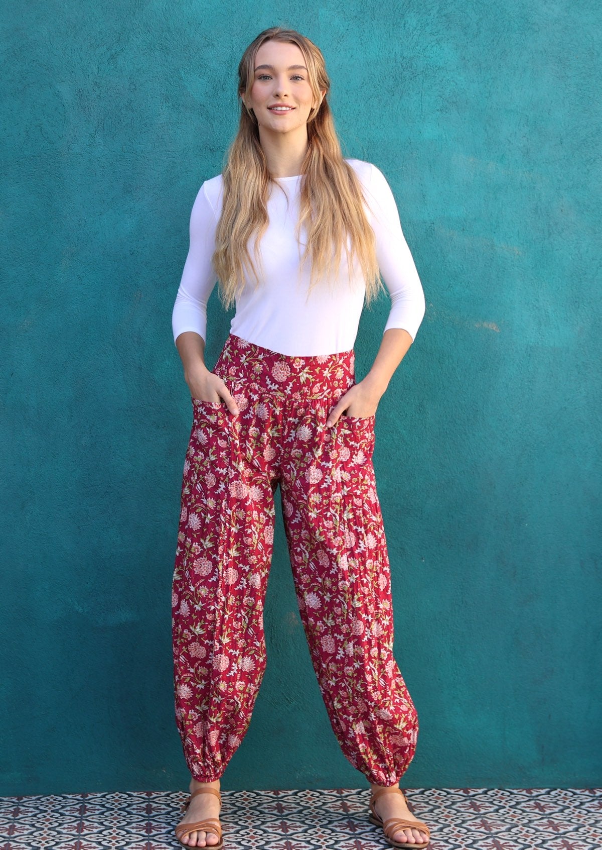 Model stands with hands in pockets wearing 100% cotton harem style pants with wide waistband and elasticated ankles.