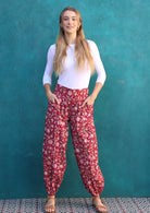 Model stands with hands in pockets wearing 100% cotton harem style pants with wide waistband and elasticated ankles.