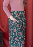 Close up image of a model wearing green cotton harem pants with wide waistband and hand in pocket.