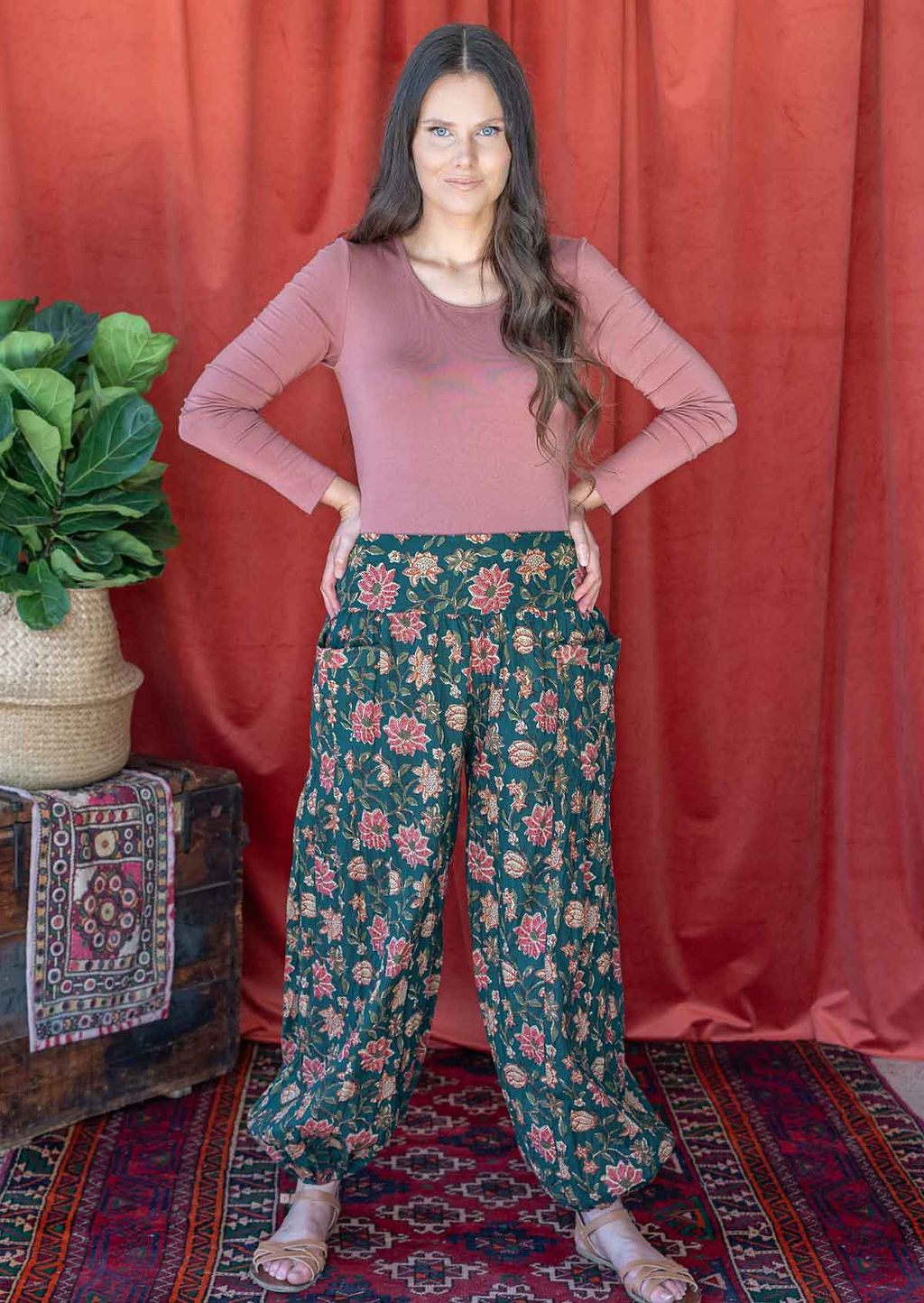 Woman posing in deep green floral printed cotton harem pants with wide flat front waistband  and elasticated ankles.