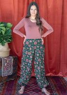 Woman posing in deep green floral printed cotton harem pants with wide flat front waistband  and elasticated ankles.