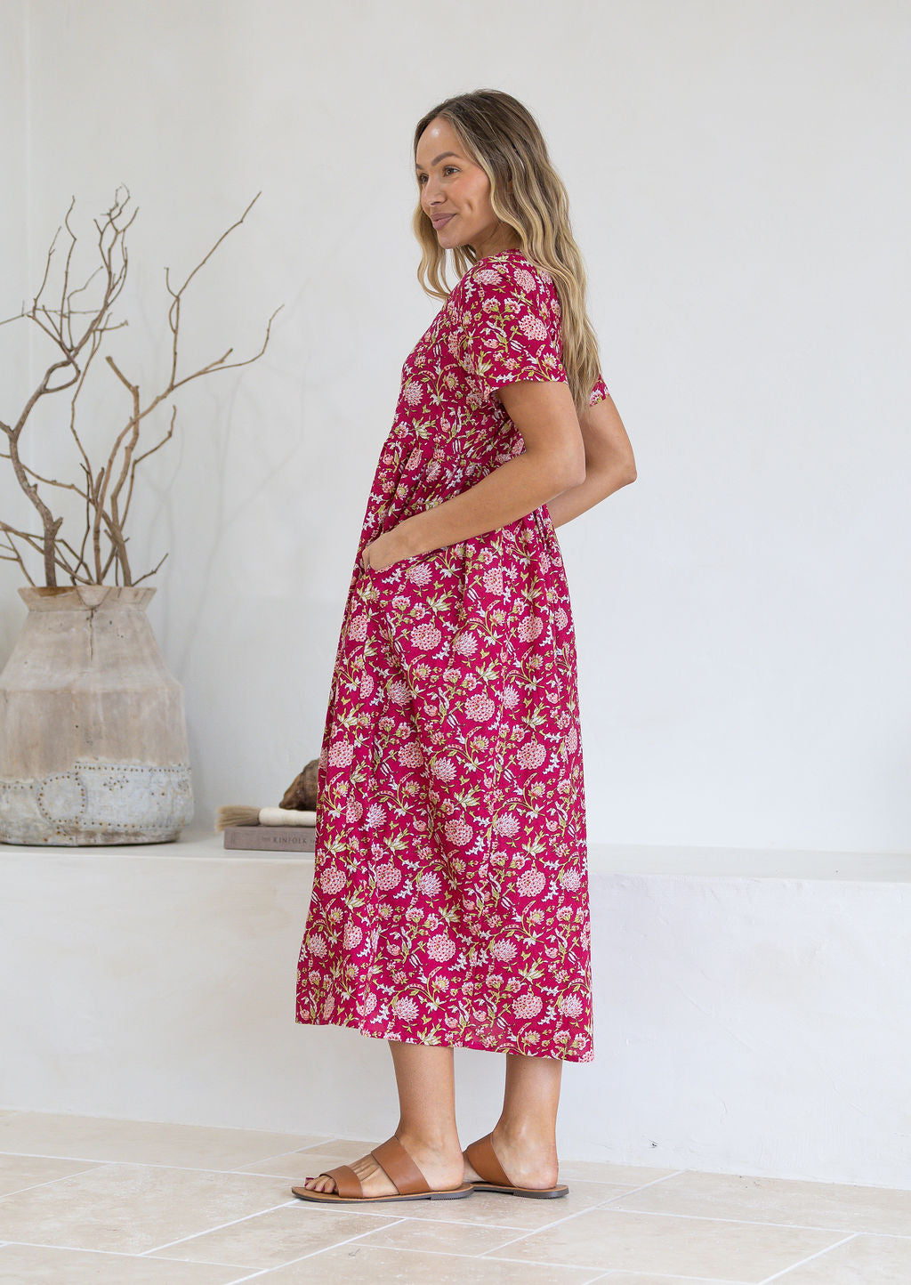Woman wearing a pink floral dress with her hand in the pocket 