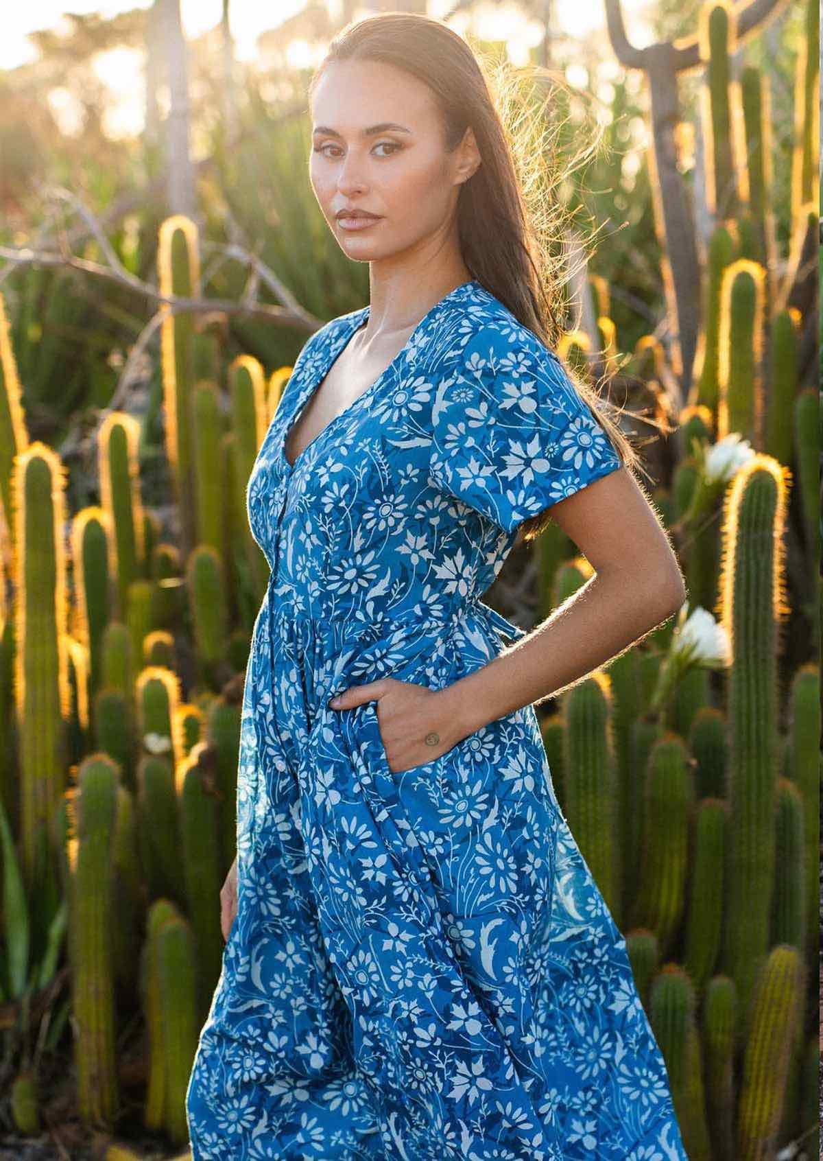  woman in blue cotton floral v neck maxi dress with hands in pocket sun in hair 