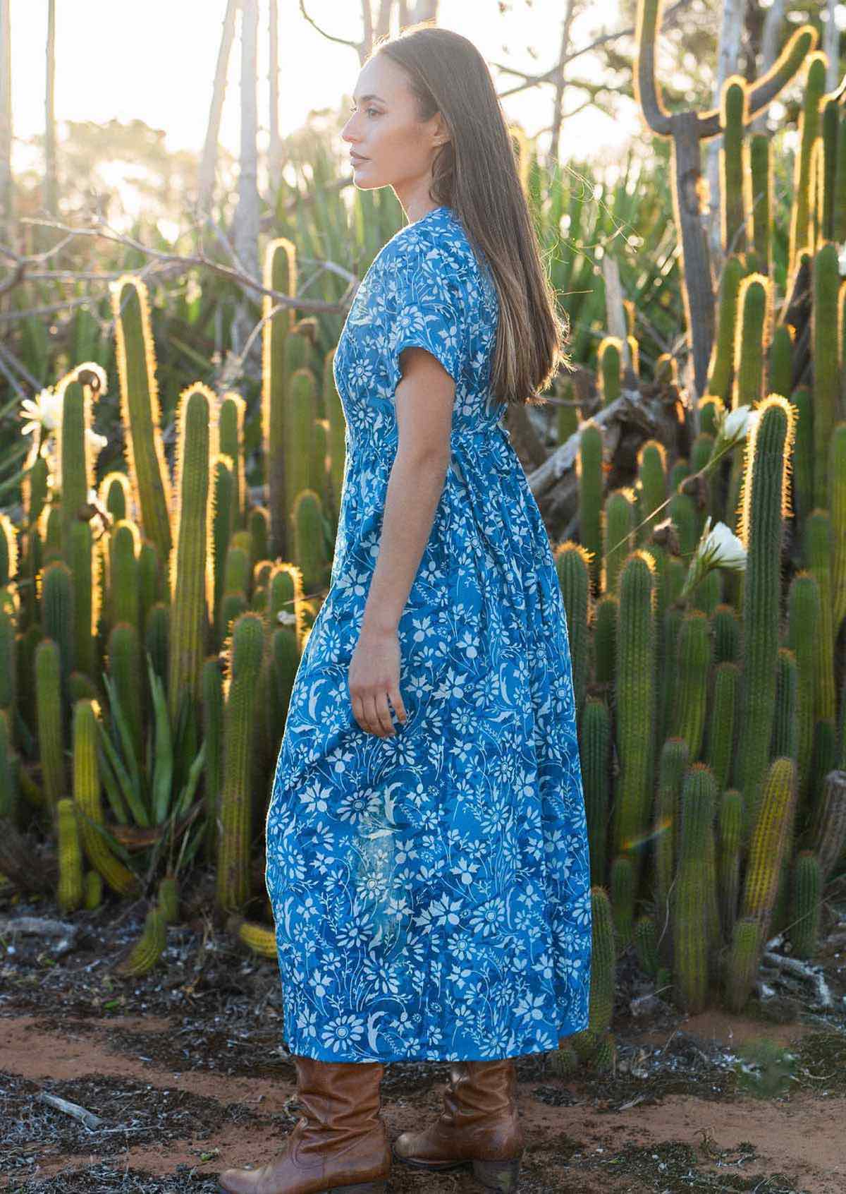 woman in blue cotton floral v neck maxi dress with hands in pocket side view 