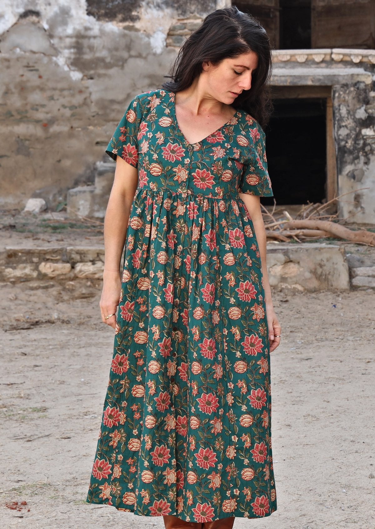 Model looking down wearing 100 percent cotton dark jade green button through v-neck dress with pockets