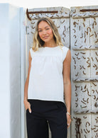 Woman wears cotton top with small gathers under the neckline yoke, both front and back, that gives this top a loose fit