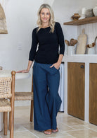Woman wearing blue cotton wide leg pants paired with a black top, with hand in pocket