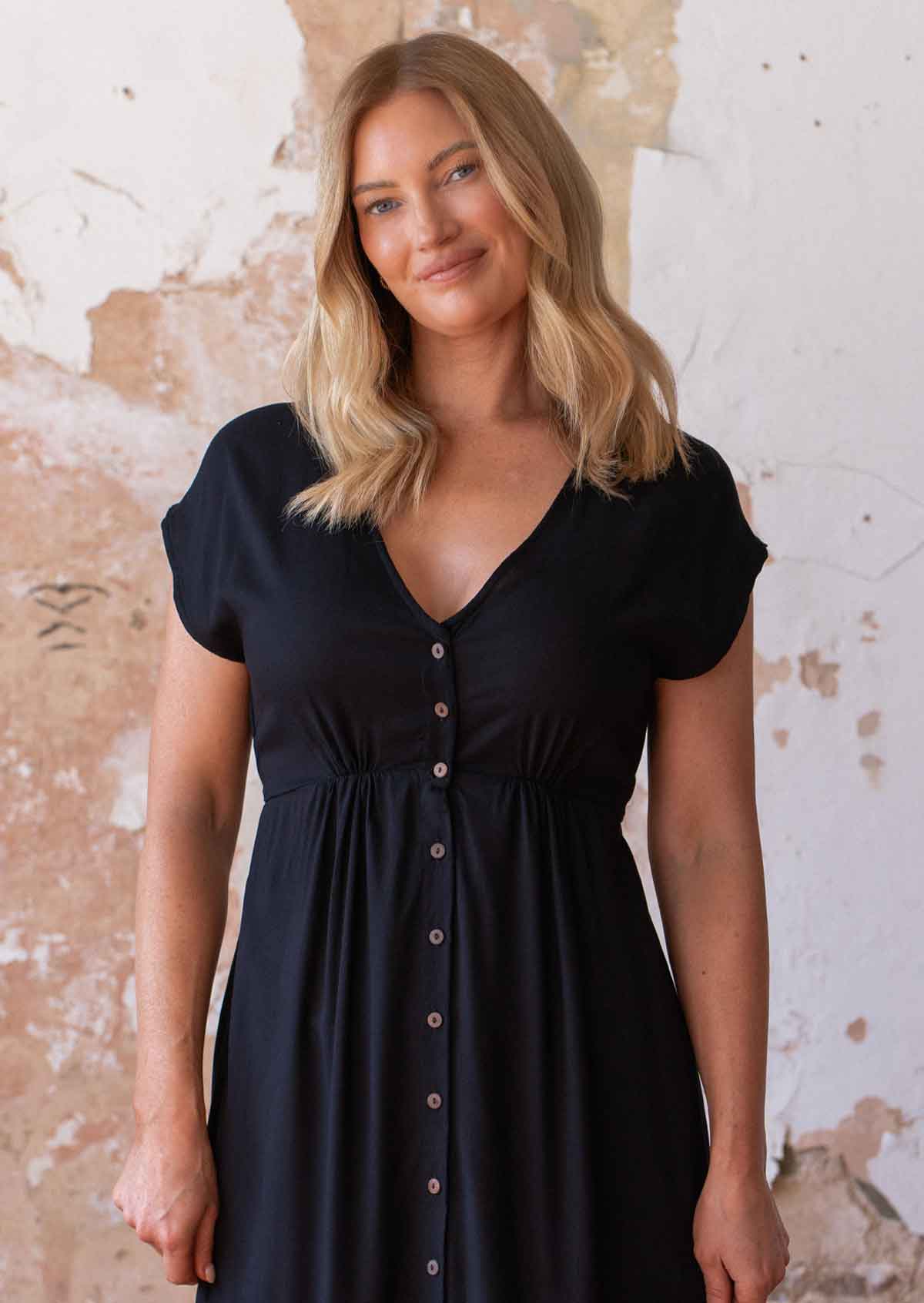 Close up of woman in black non-stretch rayon dress with V-neckline and small gathers under bust