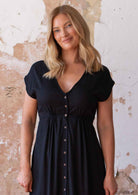 Close up of woman in black non-stretch rayon dress with V-neckline and small gathers under bust