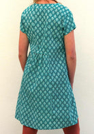 Model slightly turned wearing 100 percent cotton aqua short sleeve beach dress back view showing pleated feature 