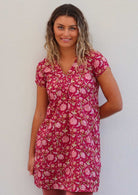 Model poses in cotton cap sleeved tunic with top-stitched V-neckline, in floral print with bright red base