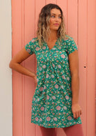 Model standing in front of pink door with one hand behind on hip wearing 100 percent cotton short sleeve tunic