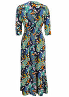 Back view of 3/4 sleeved rayon maxi dress with buttoned bodice, V-neckline and a wide shirred waistband, in a floral and peacock print on a navy base
