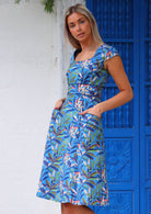 Woman wearing blue cotton retro style dress with pockets in front of blue door