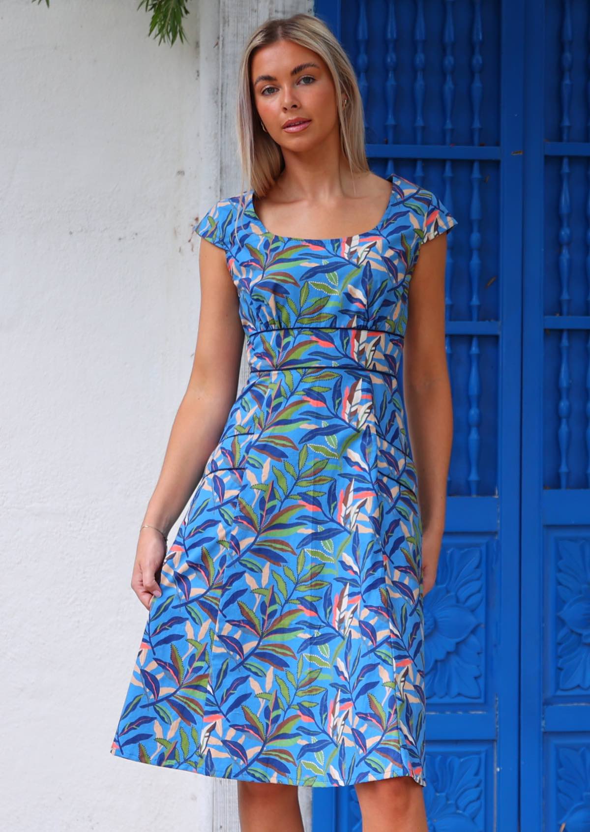 Woman wearing cotton retro style dress with pockets in front of blue door