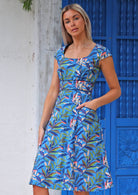 Woman wearing pure
 cotton retro style dress with pockets in front of blue door