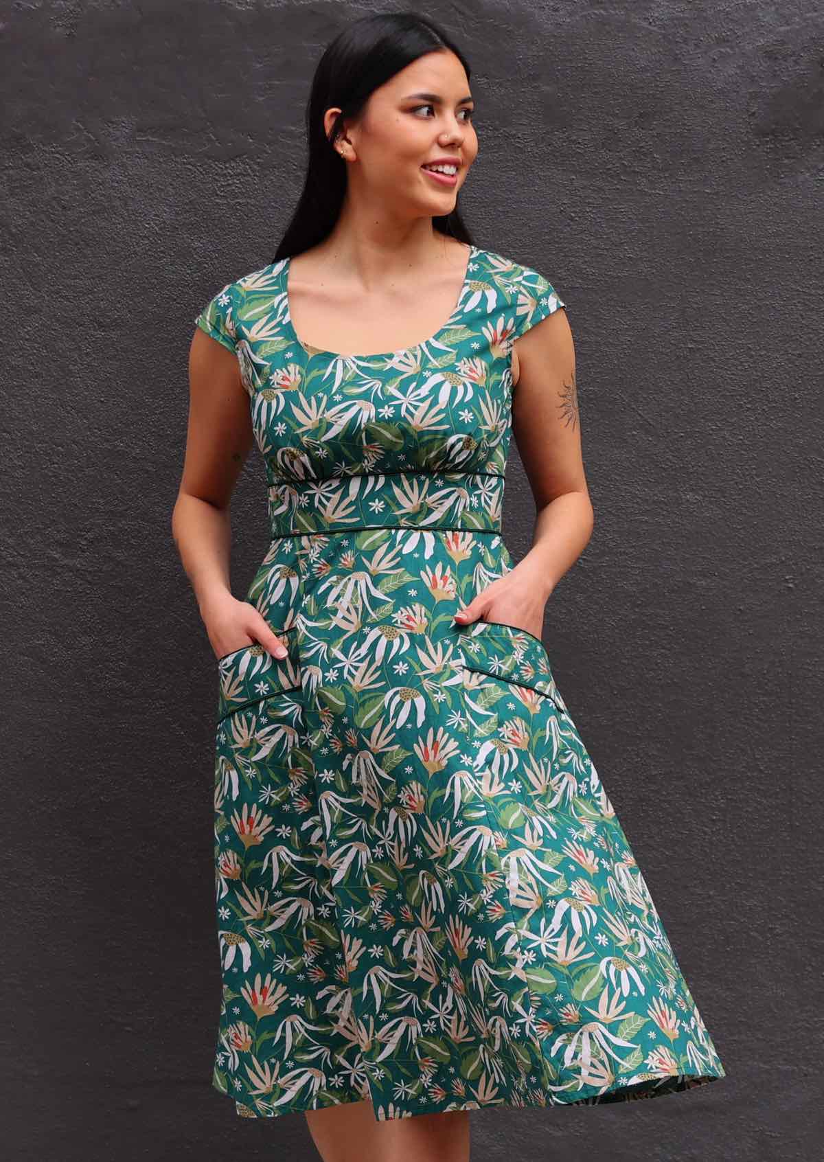 Model wearing green 100 percent cotton scoop neck retro dress with both hands in pockets 