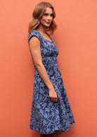 Woman standing side view wearing the Scarlett Dress Neela print 100 percent cotton retro dress navy floral print 