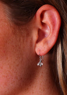 tiny silver bee earrings on women's ear
