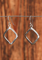 92.5% silver dangly diamond earrings sitting on wire for display.
