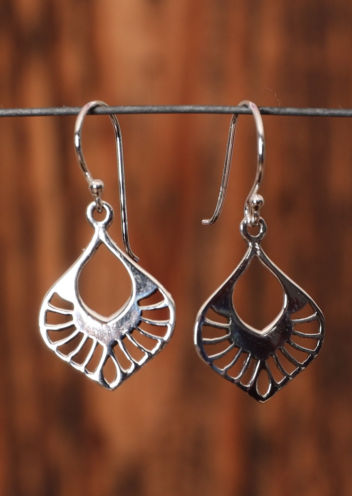 92.5% silver flat nouveau earrings sit on a wire for display.