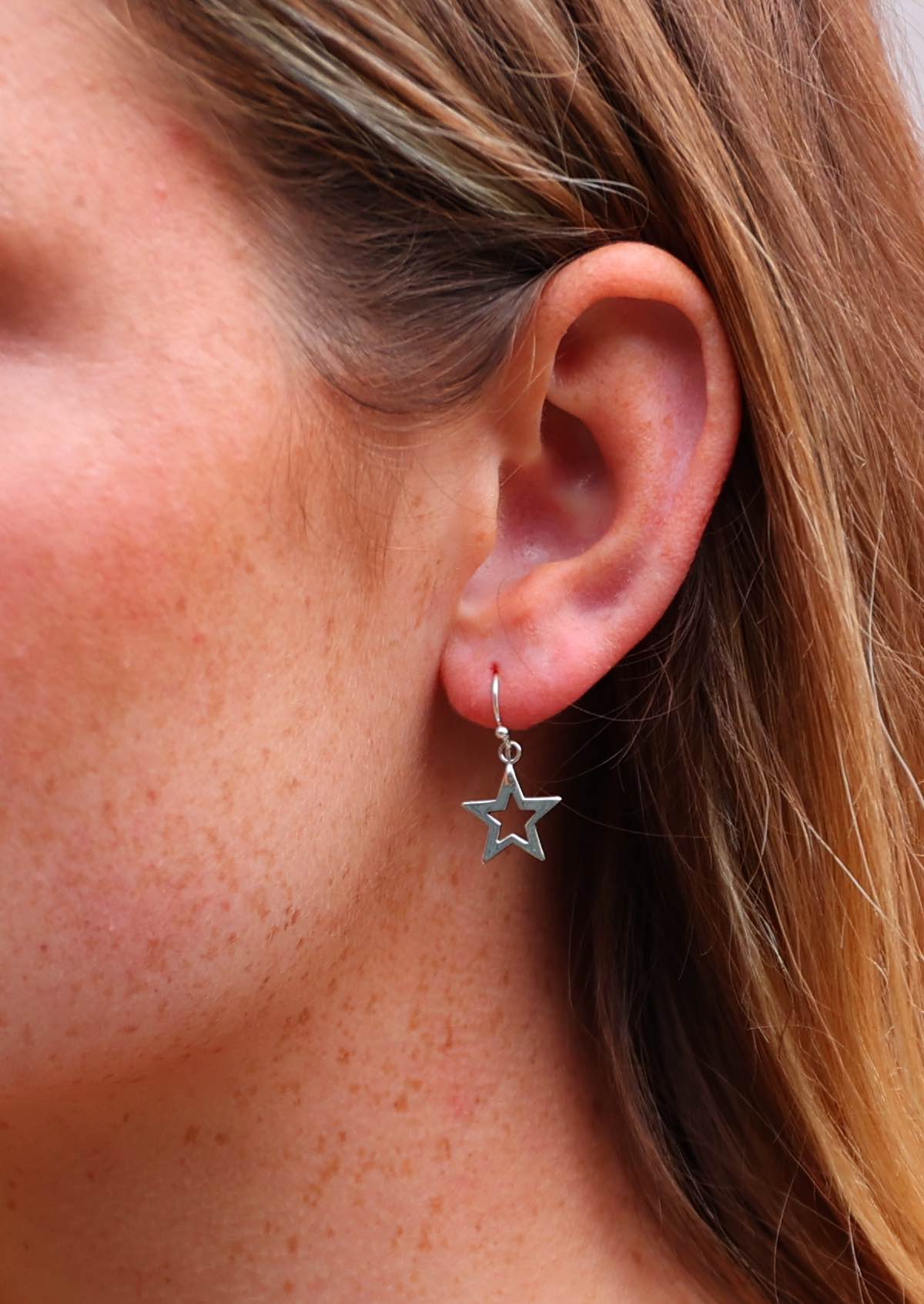 Close up of silver five point star earring with hole in the centre