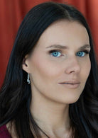 woman wearing dangly silver treble cleft music earring 
