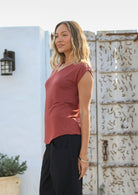 Woman wearing a 100% rayon terracotta V-neck top and black cotton pants standing outdoors.